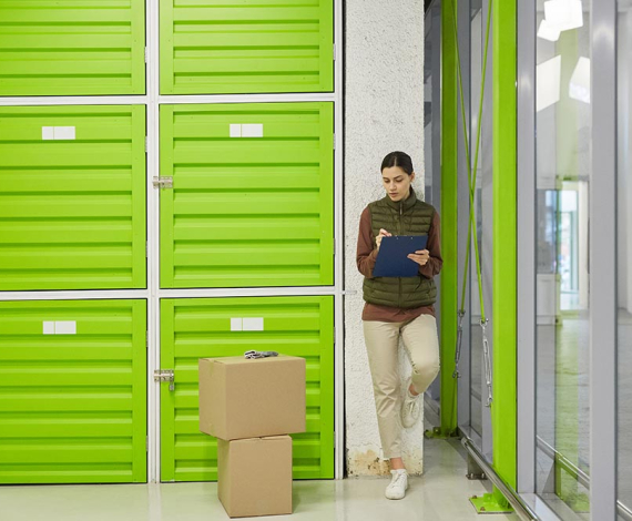 Young worker making notes in document she registrating parcels before delivery in warehouse